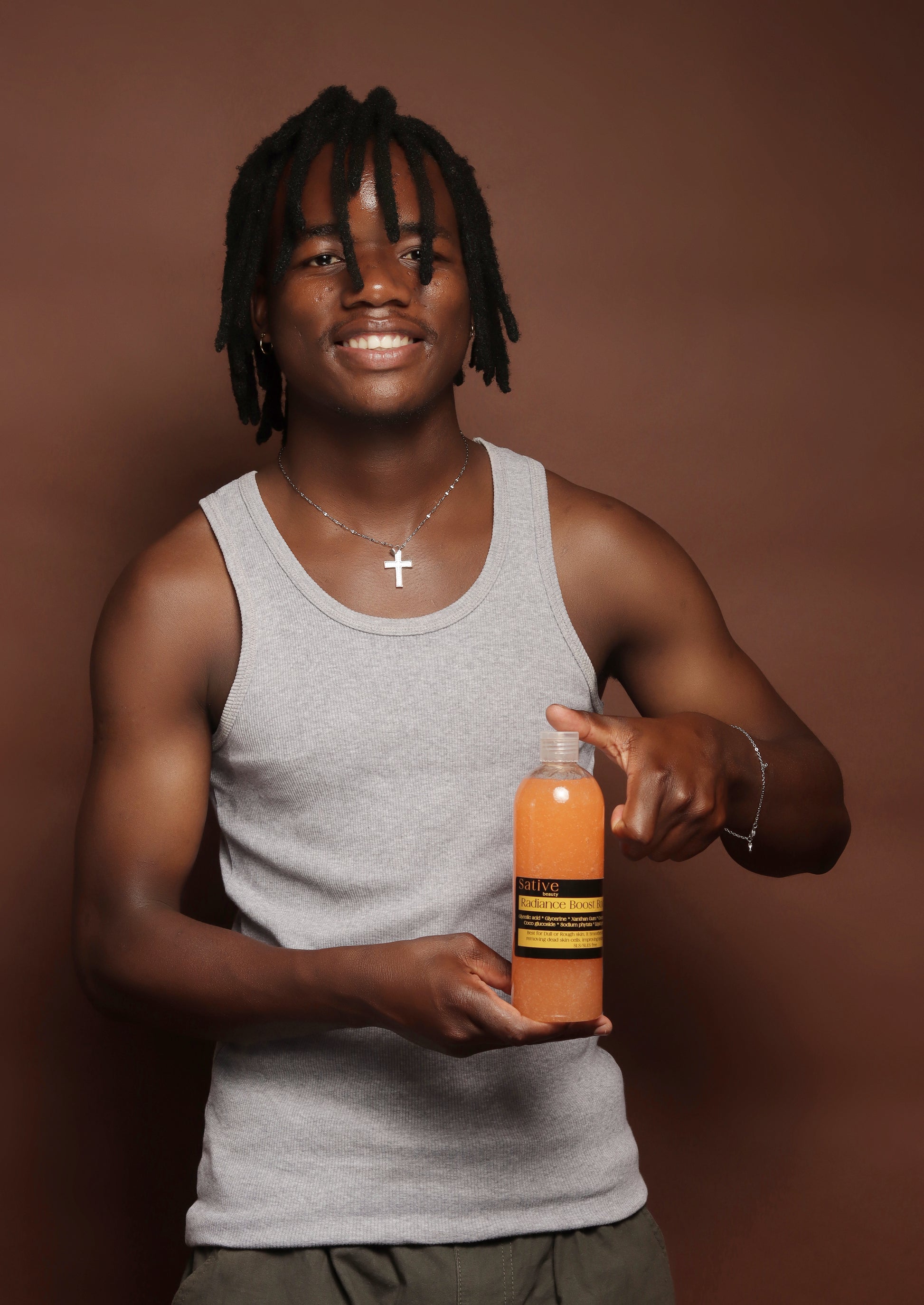 Person holding a Radiance Boost Body Wash bottle with a brown background