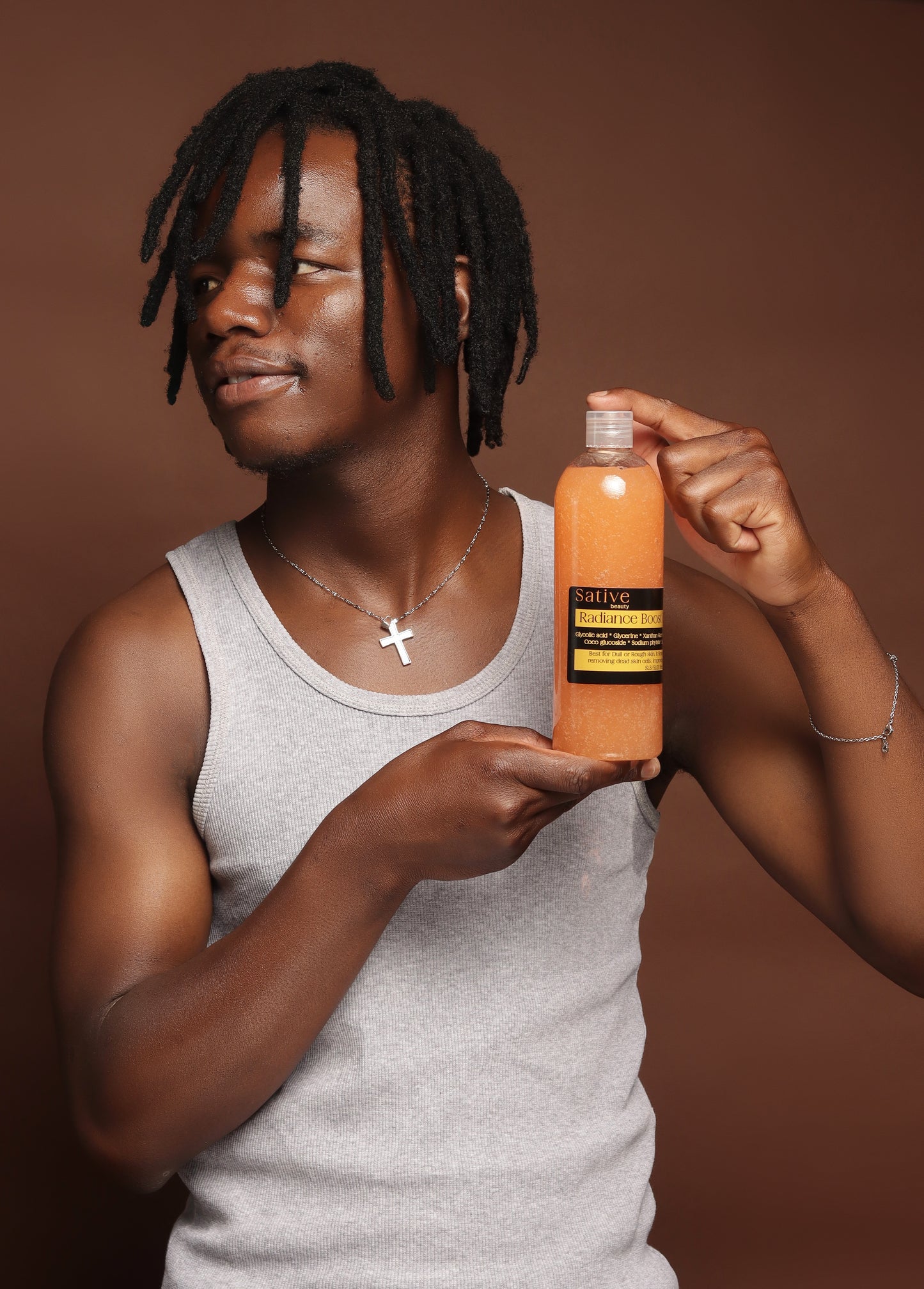 Person holding a bottle of Sative skin care product against a brown background
