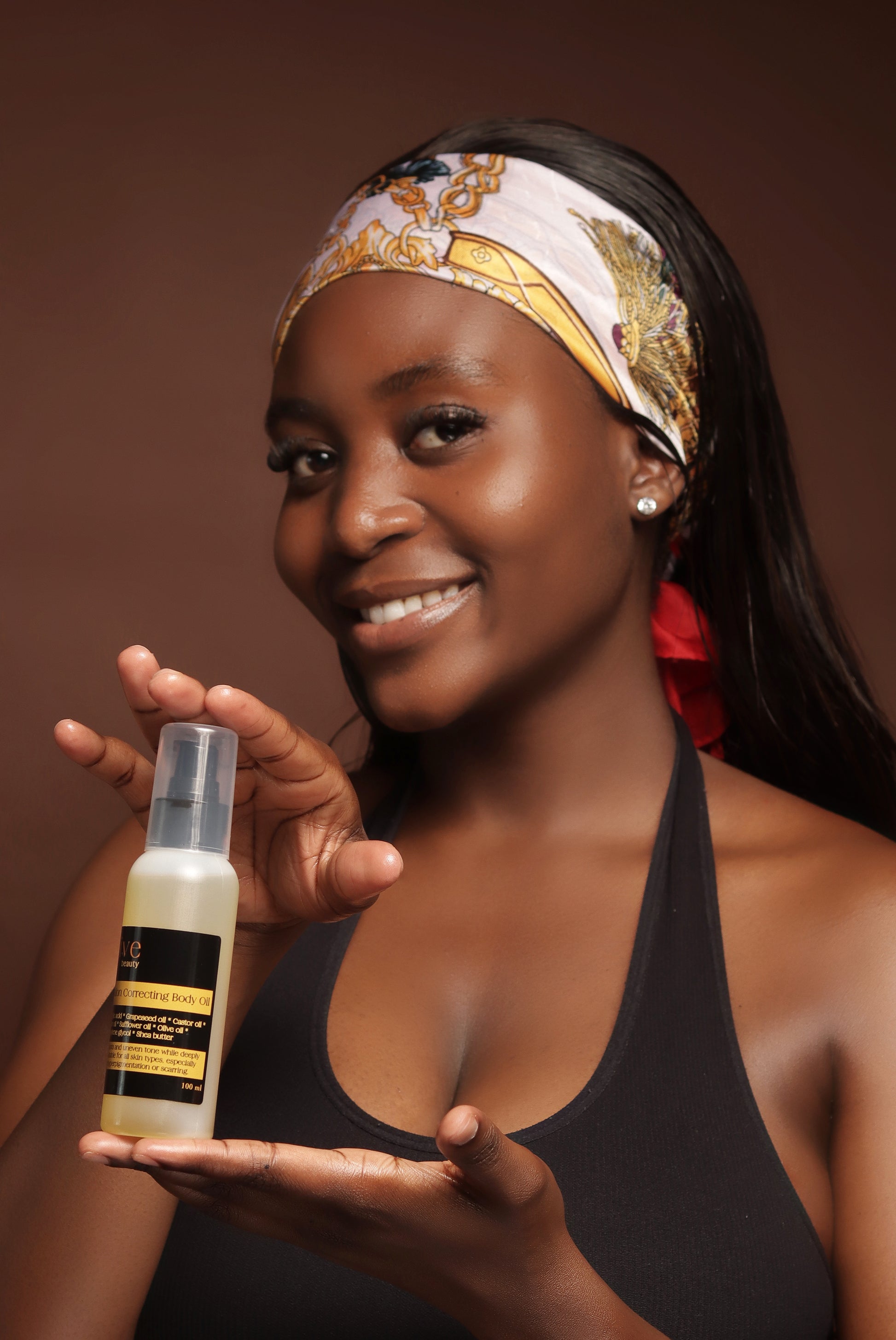 Woman holding a skincare product against a brown background