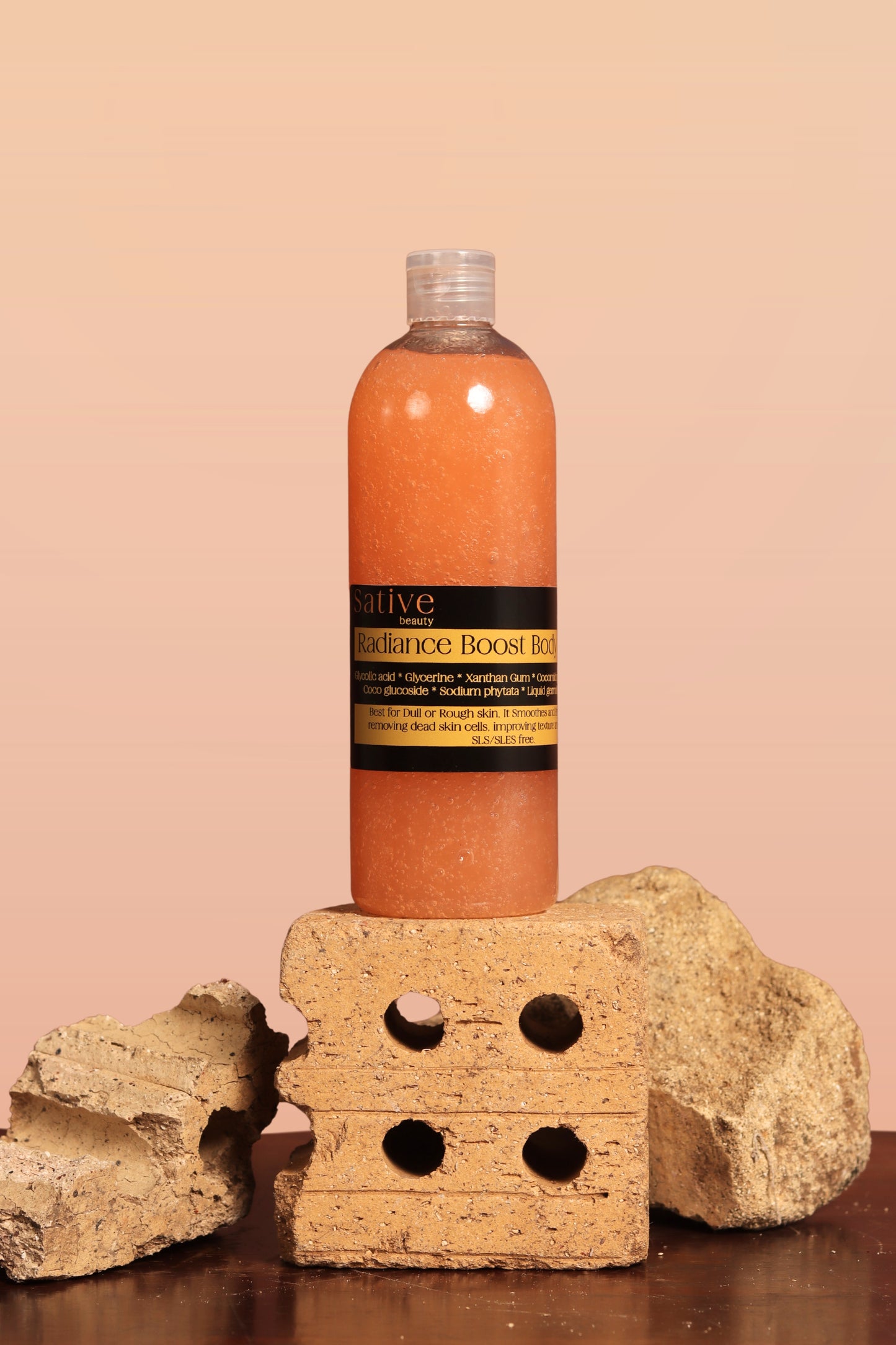 Bottle of Sative Beauty's Radiance Boost Body Wash on a stone block with a beige background