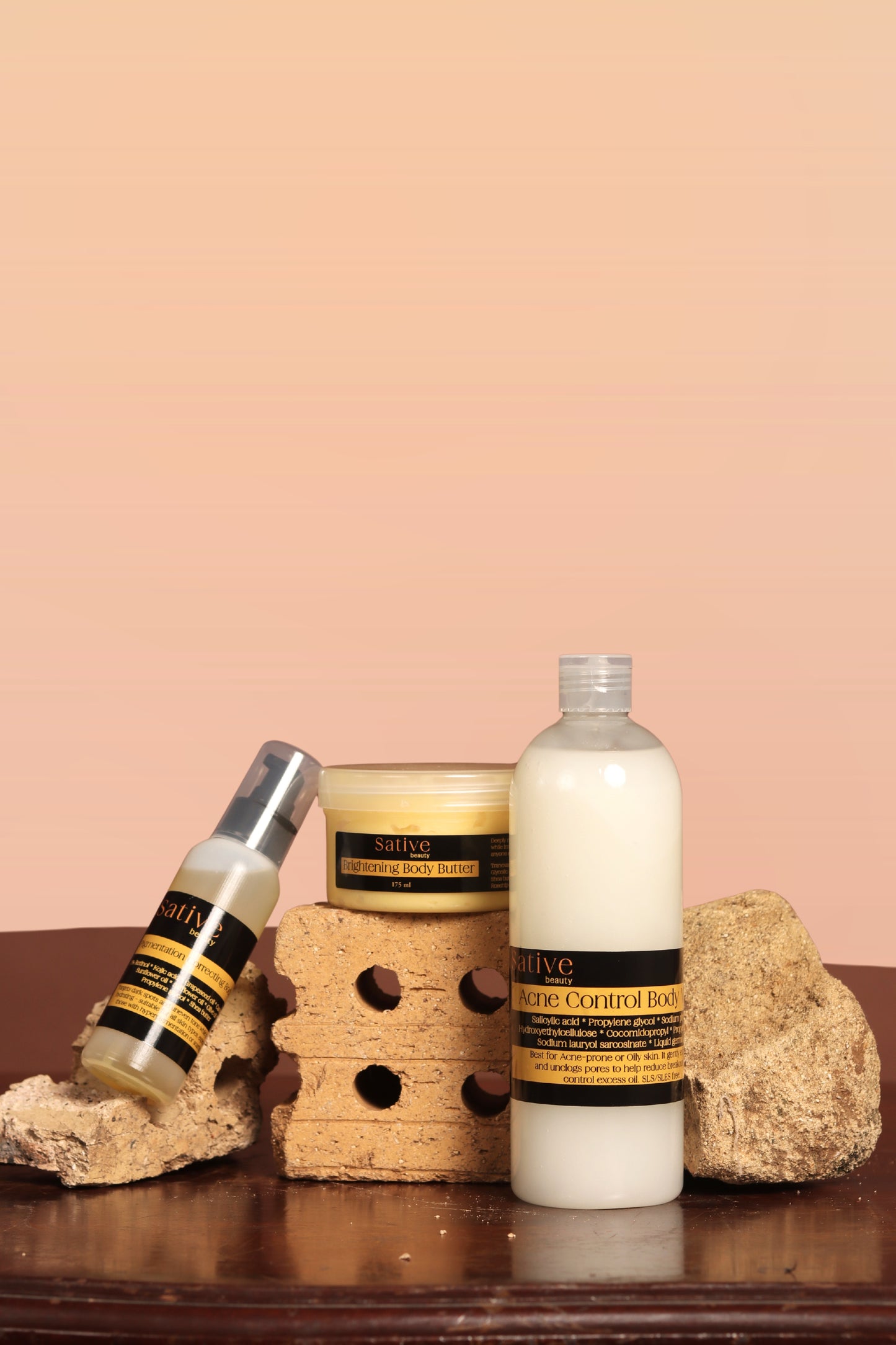 Skincare products including a bottle, jar, and cream on a wooden surface with a pink background