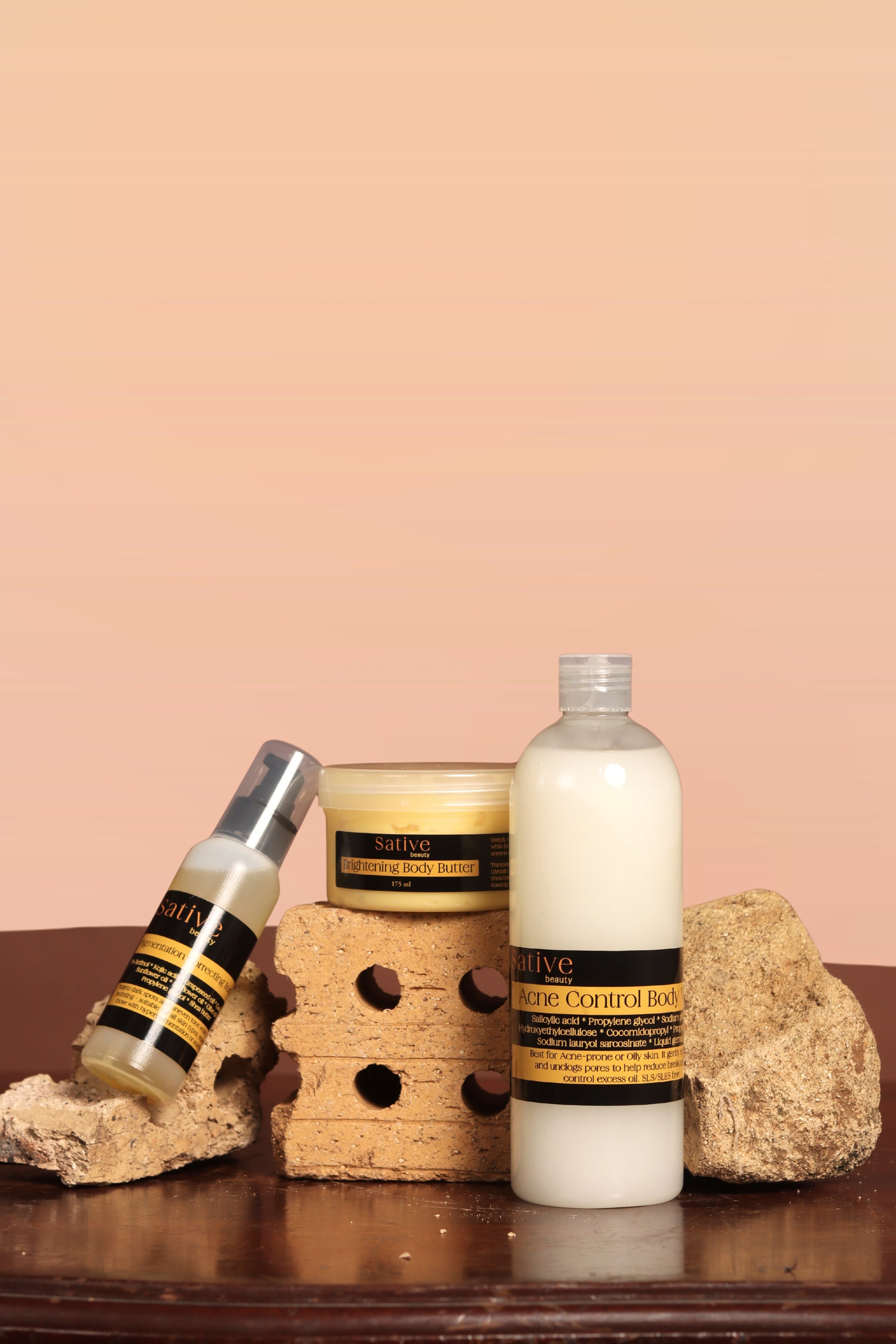 Skincare products including a bottle, jar, and cream on a wooden surface with a pink background