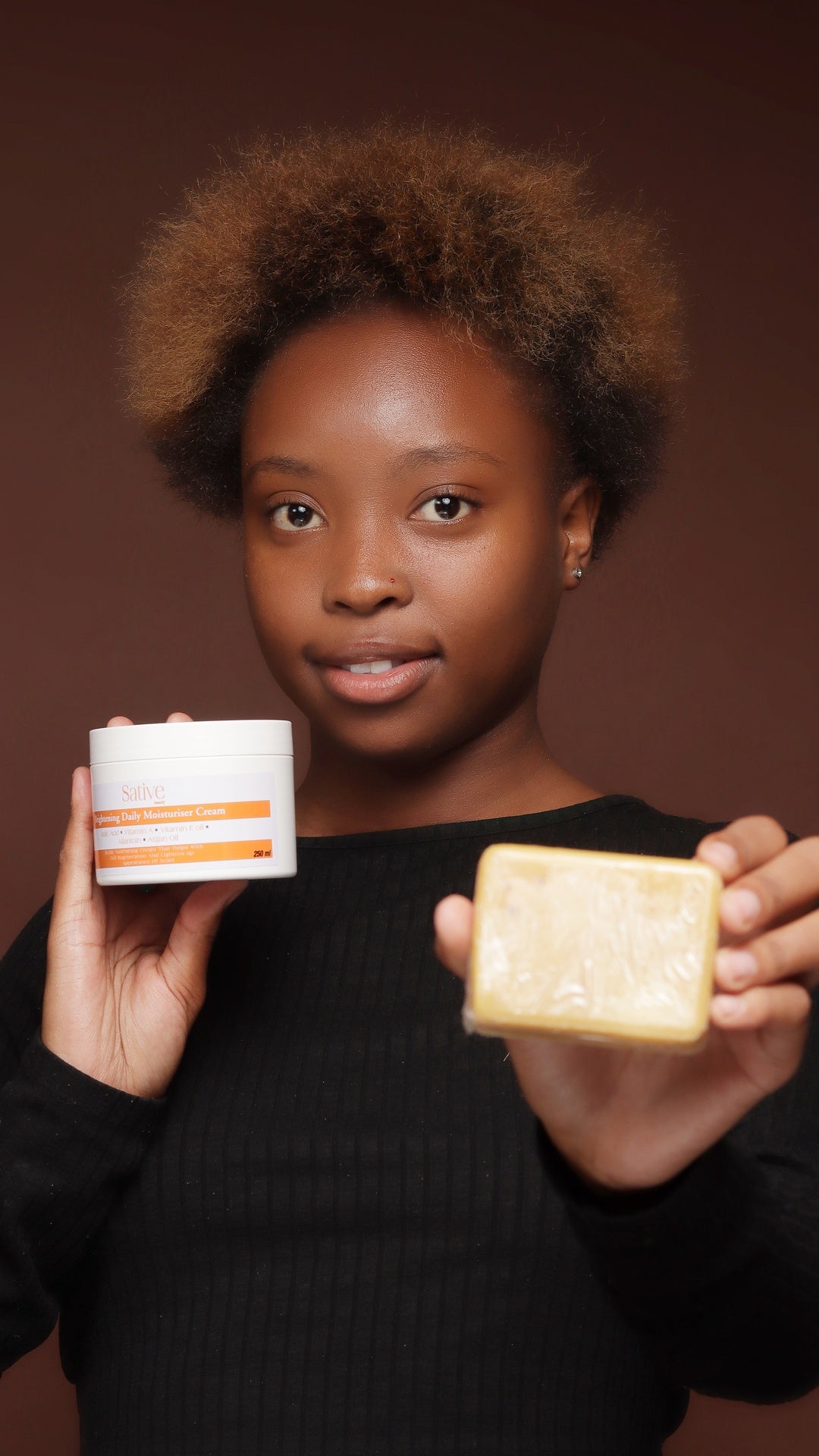 Young lady holding goat milk soap and brightening moisturiser cream