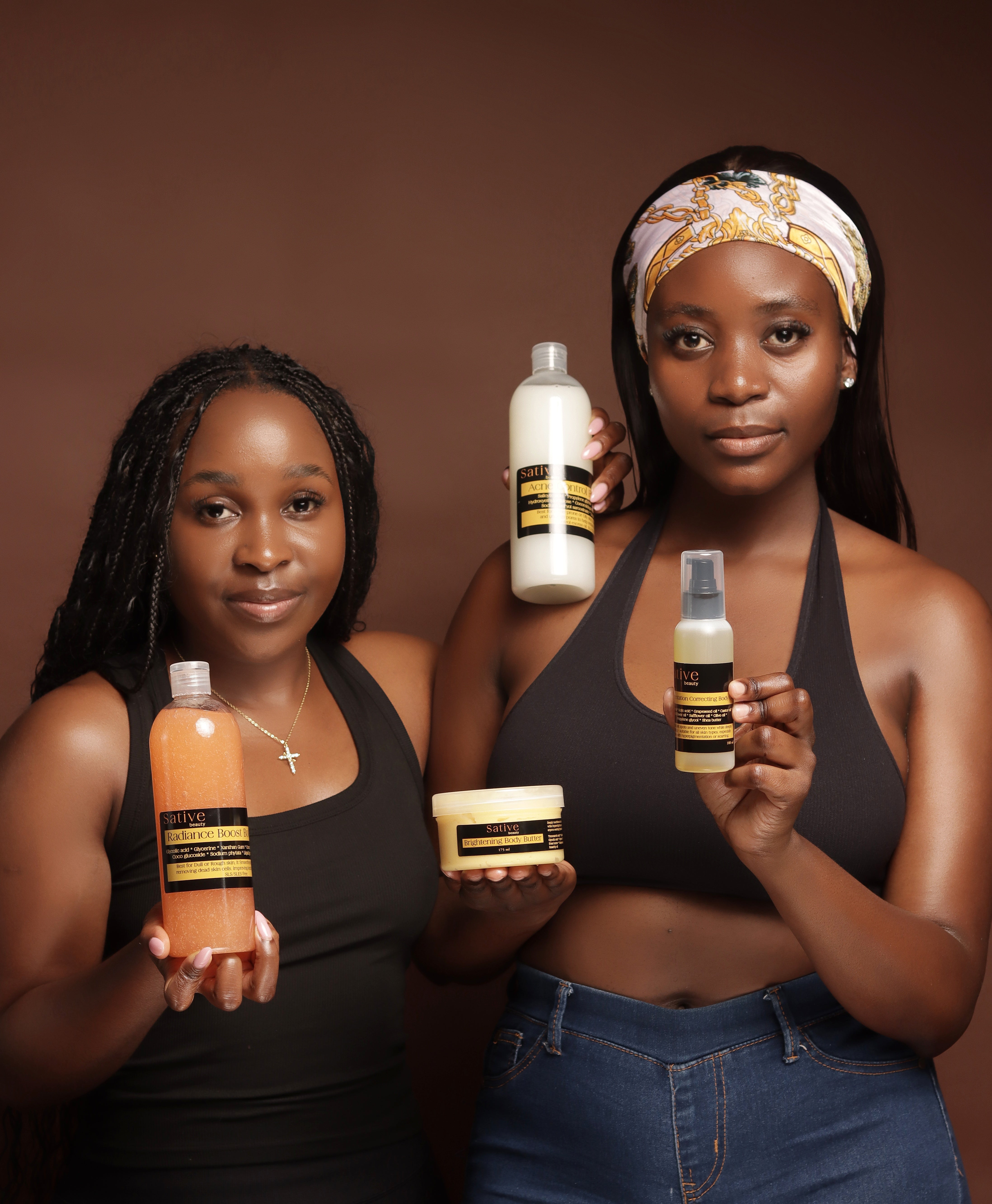 Two women holding skincare products against a brown background