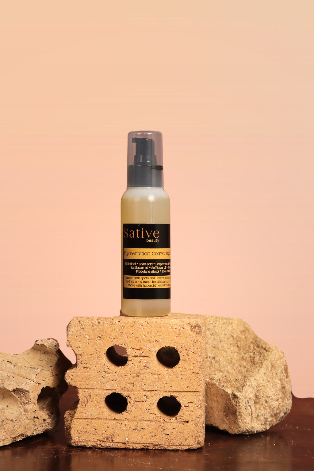 Bottle of Pigmentation Correcting Body Oil product on a brick with a beige background