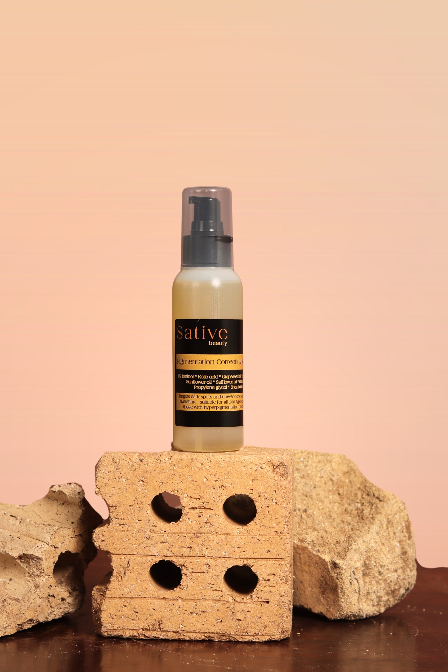 Bottle of Pigmentation Correcting Body Oil product on a brick with a beige background
